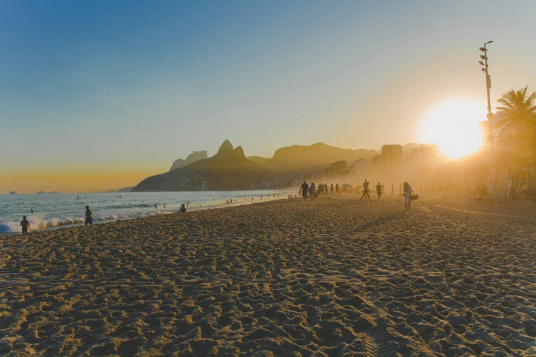 a group of people standing on top of a sandy beach, by Felipe Seade, pexels contest winner, rio de janeiro, evening sunlight, olympics, vibrant scene