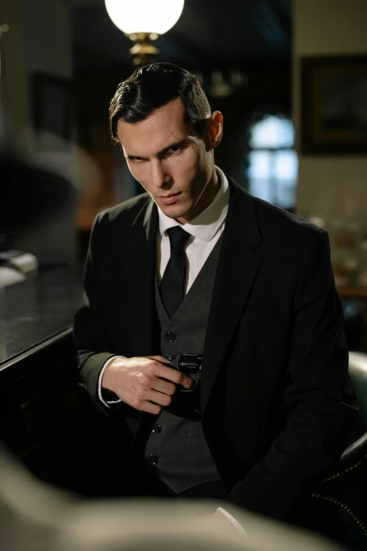 a man in a suit sitting at a bar, inspired by Ramon Pichot, benedict cumberbatch, man with a gun, victorian inspired clothing, tense look