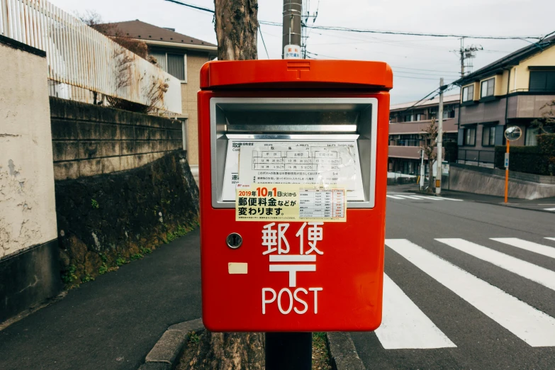 a red post box sitting on the side of a road, a polaroid photo, by Yasushi Sugiyama, unsplash contest winner, ethnicity : japanese, 🚿🗝📝, japanese pottery, newspaper