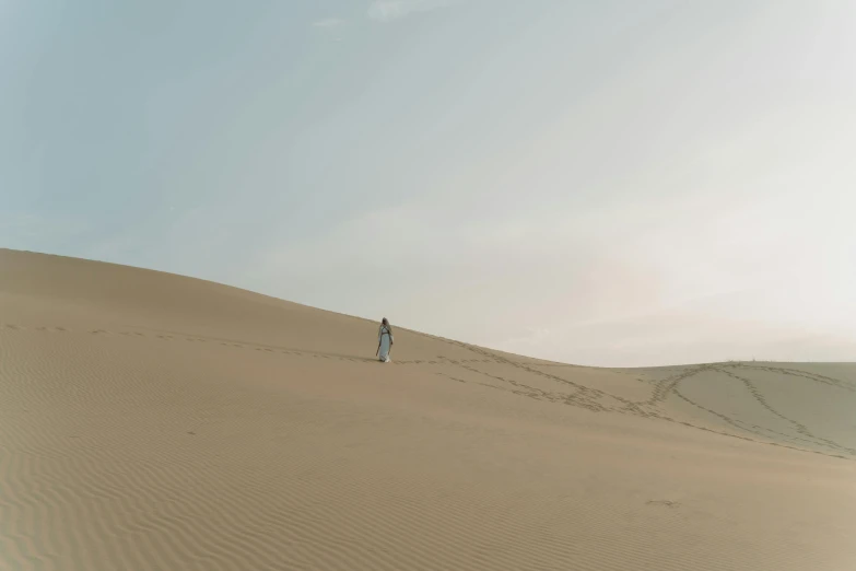a person standing on top of a sand dune, long flowing white robe, a woman walking, taken on iphone 1 3 pro, high res 8k