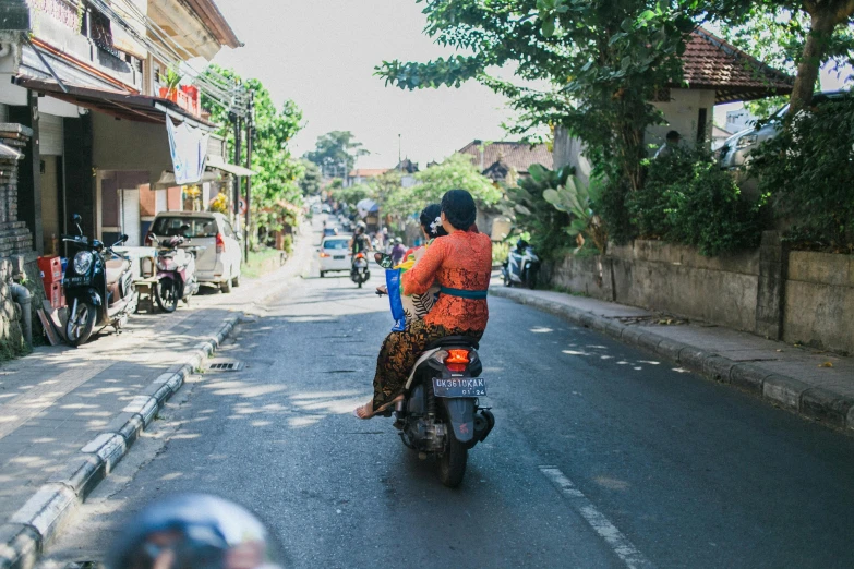 a man riding on the back of a motorcycle down a street, by Daniel Lieske, pexels contest winner, batik, wearing a sari, walking through a suburb, 🦩🪐🐞👩🏻🦳