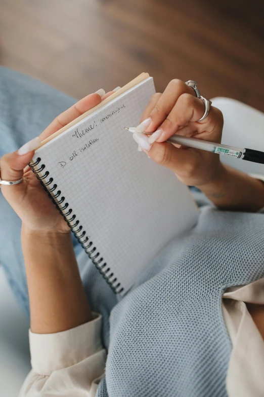 a woman holding a pen and writing in a notebook, by Robbie Trevino, handcrafted, on high-quality paper, really realistic, charts