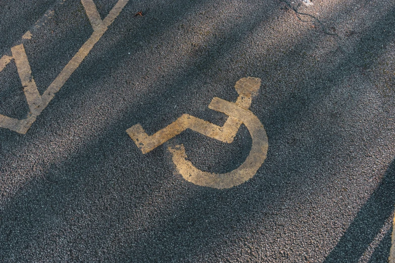 a handicap sign painted on the side of a road, unsplash, graffiti, square, brown, automobile, splash image