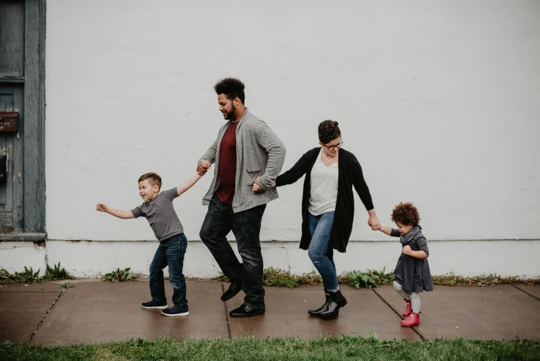 a family walking down a sidewalk holding hands, by Carey Morris, pexels contest winner, on a gray background, casual game, varying ethnicities, fun pose