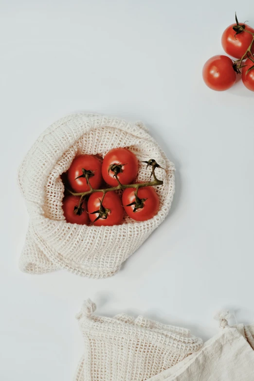 a bag of tomatoes sitting on top of a table, a still life, unsplash, made of wool, white backround, 6 pack, cowl