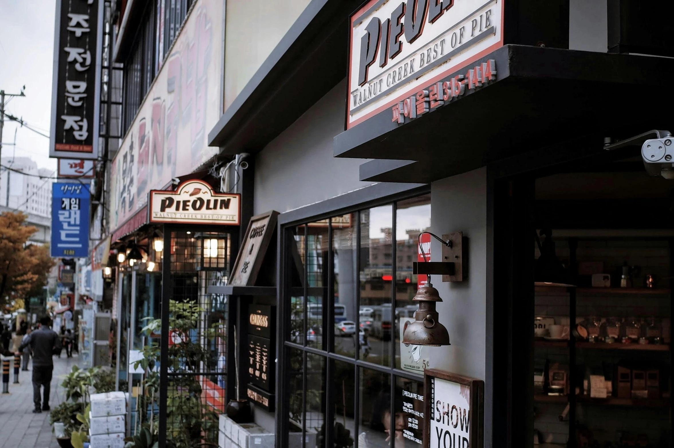 a group of people walking down a sidewalk next to a store, pexels contest winner, private press, old signs, epicurious, black and terracotta, pixivs and