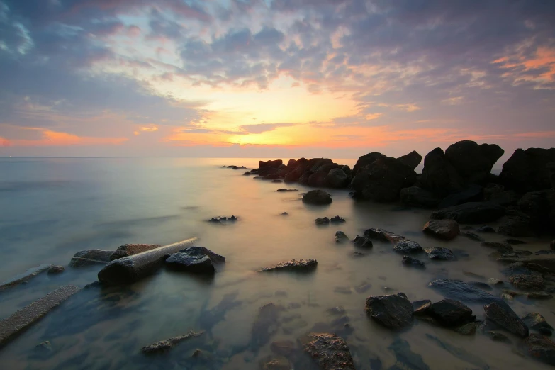 a sunset over the ocean with rocks in the foreground, by Jesper Knudsen, medium format, grey, cute photo