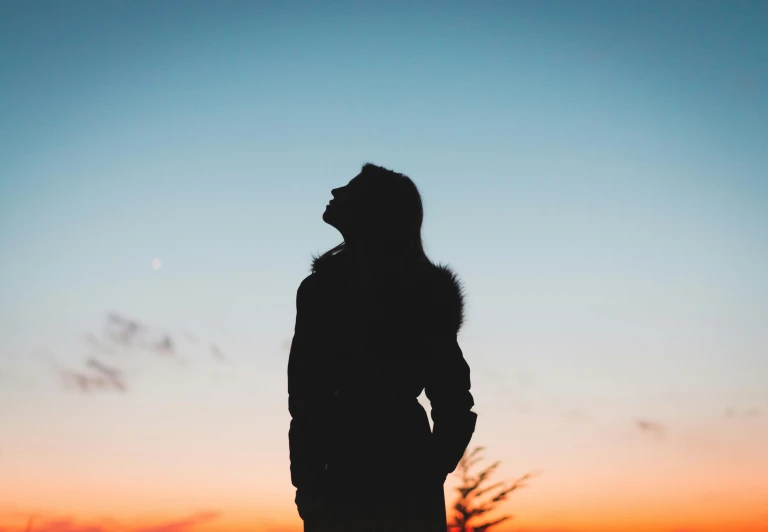 a silhouette of a person standing in front of a sunset, young woman looking up, portrait featured on unsplash, backlit shot girl in parka, profile image