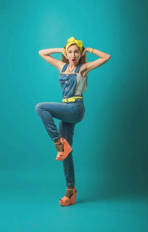 a woman in overalls is posing with her hands on her head, inspired by Jean Hey, pexels, pop art, dynamic pose full body, vibrant.-h 704, full body with costume, blippi