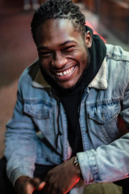 a man smiles as he sits on a bench, an album cover, by Stokely Webster, trending on pexels, grime, lights on, headshot profile picture, godwin akpan