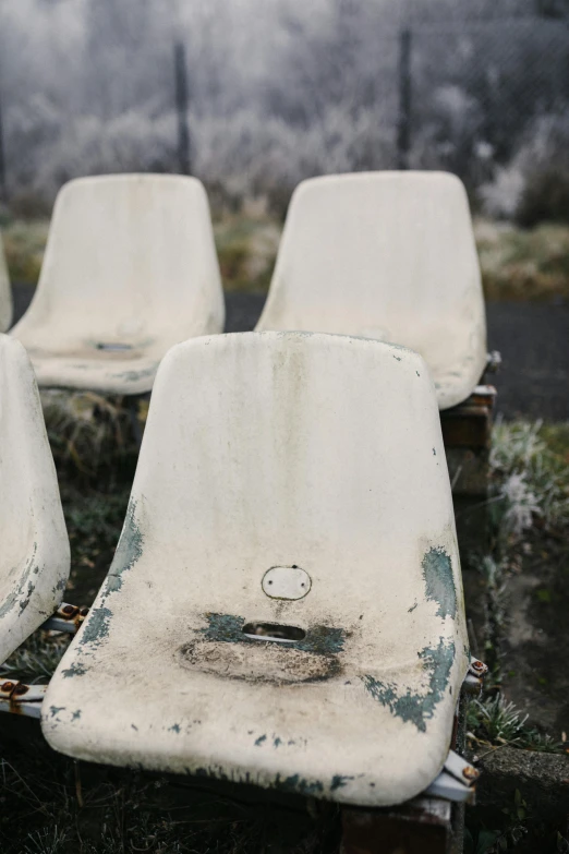 a row of white chairs sitting on top of a grass covered field, an album cover, inspired by William Congdon, trending on unsplash, conceptual art, snowing frozen ice, fused aircraft parts, portrait of a slightly rusty, sport