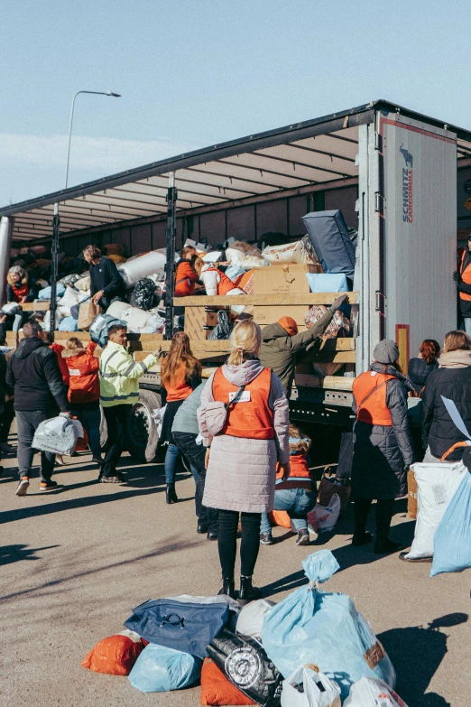 a group of people standing in front of a truck, by karlkka, temporary emergency shelter, with a bunch of stuff, orange, scandinavian