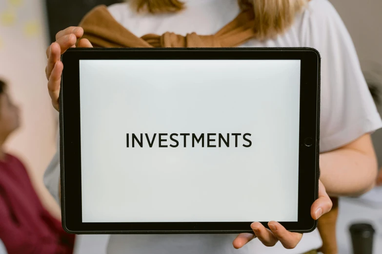 a woman holding a tablet with the word investments on it, a portrait, by Carey Morris, pixabay, incoherents, instagram post, wide screenshot, rectangle, alessio albi