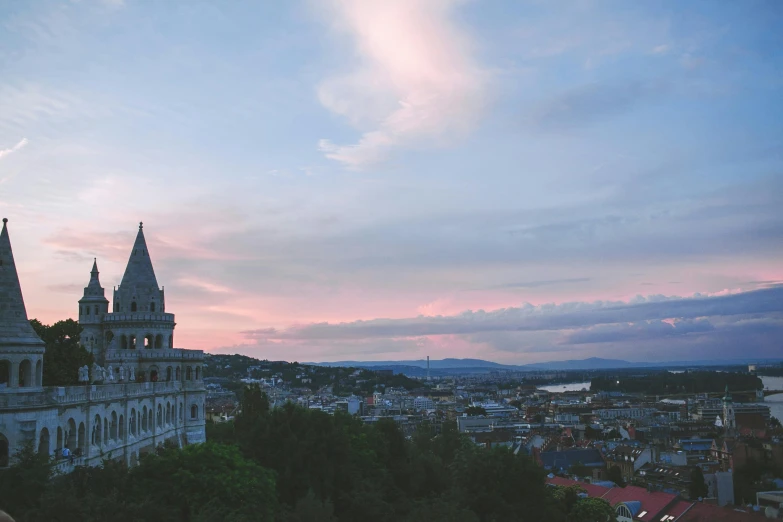 a large building sitting on top of a lush green hillside, by Emma Andijewska, unsplash contest winner, baroque, evening sky, budapest, pink, grey