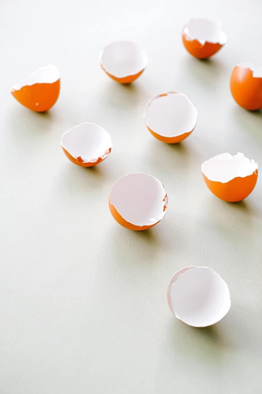 a group of broken eggs sitting on top of a table, unsplash, process art, made from paper, white and orange, ilustration, smooth round shapes