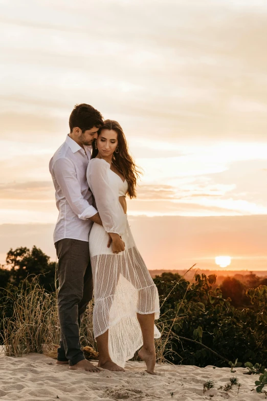 a man and woman standing on top of a sandy hill, stunning elegant pose, sun setting, alana fletcher, overlooking