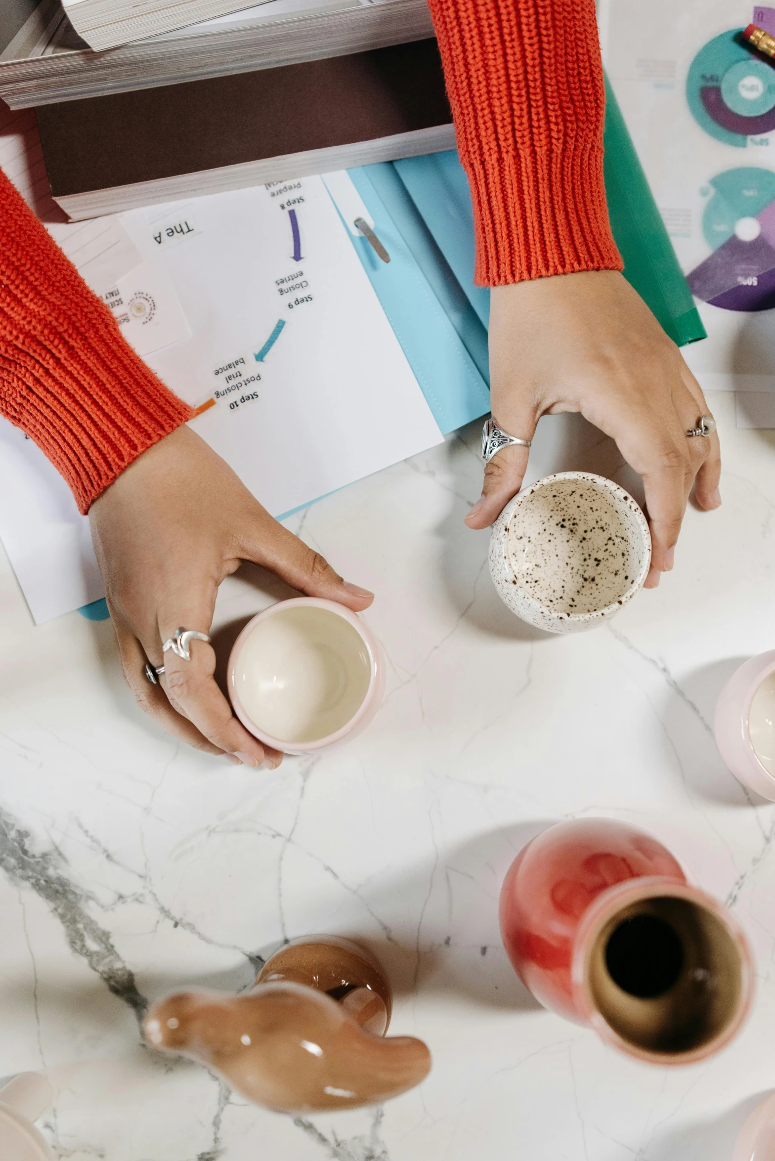 a woman sitting at a table with a cup of coffee, process art, cups and balls, all marble, hands on counter, inspect in inventory image