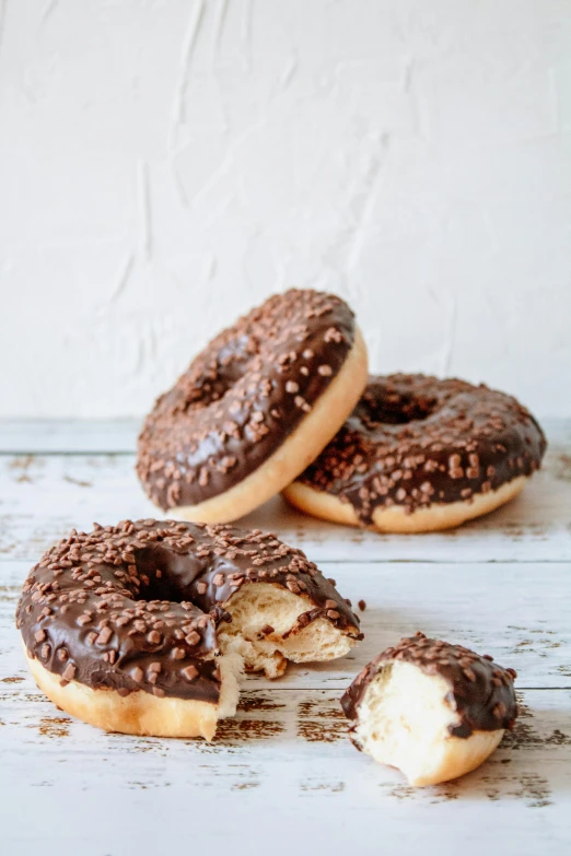 a couple of doughnuts sitting on top of a wooden table, smothered in melted chocolate, 3 - piece, 6 pack, seeds