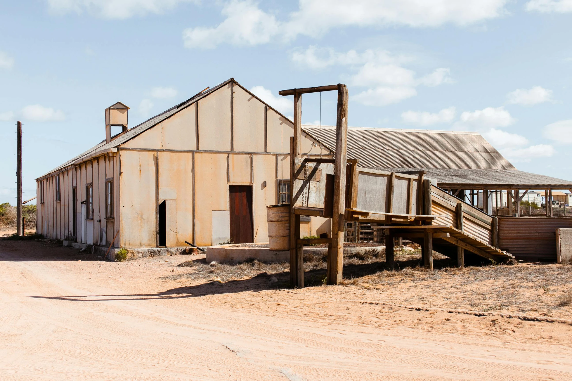 an old building sitting on the side of a dirt road, iron smelting pits, classic cinema, muted browns, dune