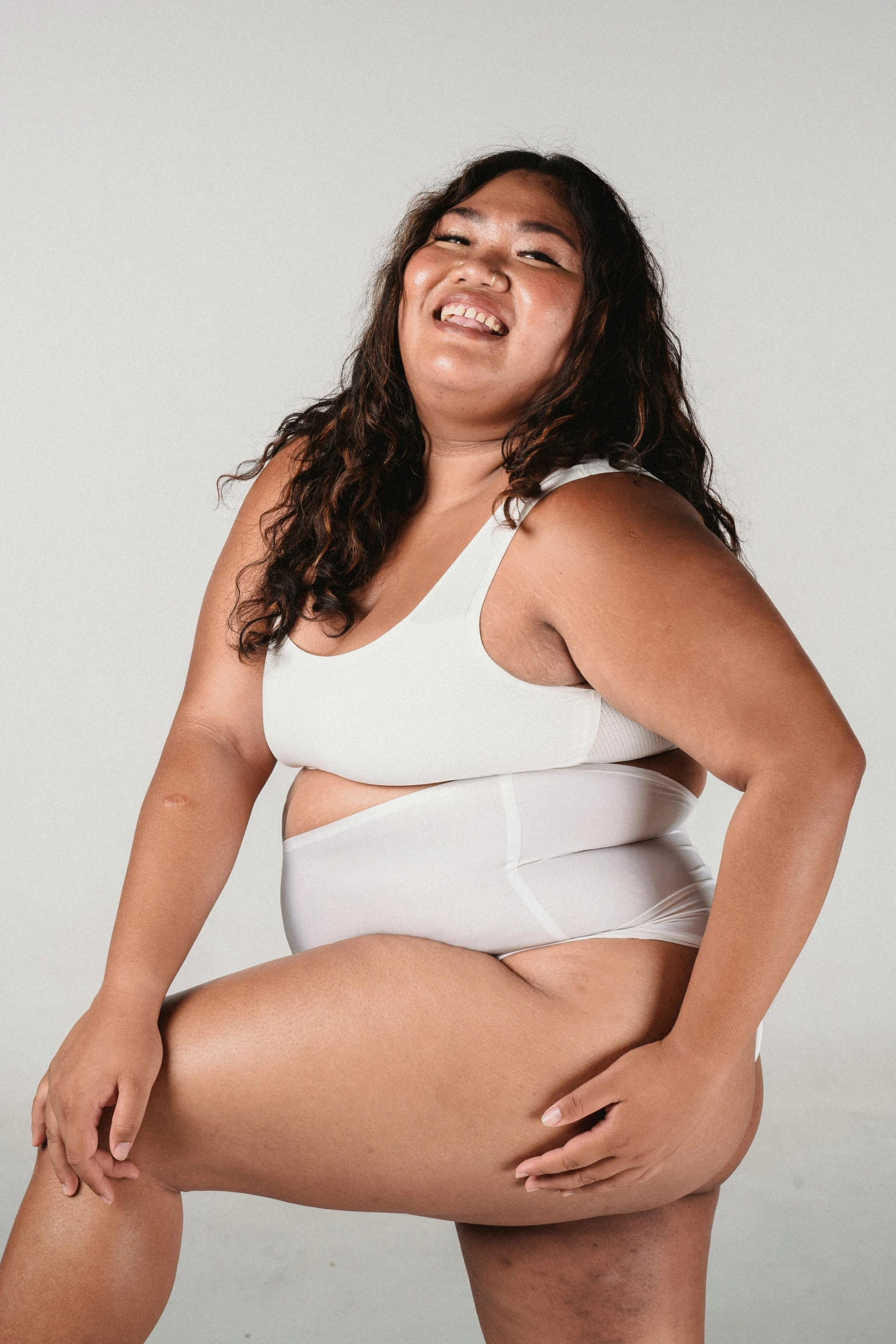 a woman in a white tank top posing for a picture, an album cover, trending on pexels, obese ), joy ang, white loincloth, laughing