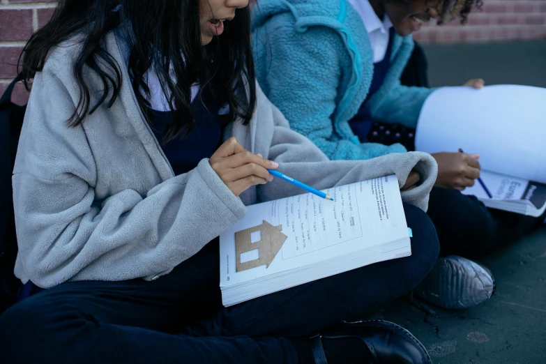 a group of girls sitting next to each other on the ground, pexels contest winner, quito school, found schematic in a notebook, people looking at a house, close up shot from the side, holding a clipboard