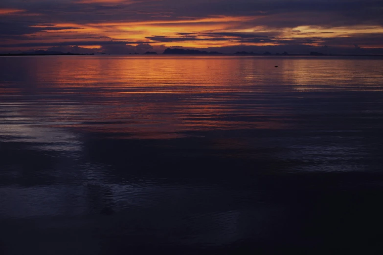 a large body of water with a sunset in the background, pexels contest winner, minimalism, dark orange night sky, ocean pattern and night sky, glassy reflections, shot on hasselblad