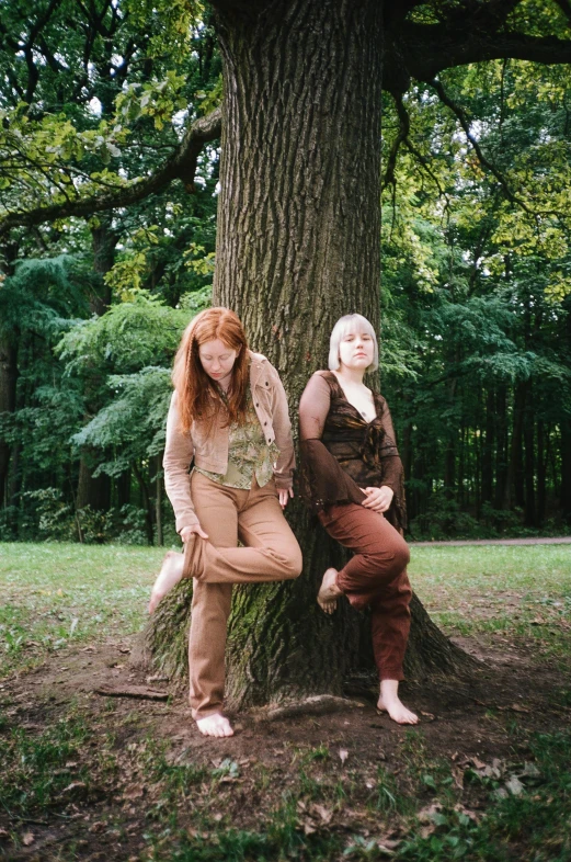 a couple of women sitting on top of a tree, an album cover, unsplash, renaissance, ginger hair, taken in the mid 2000s, brown clothes, very very low quality picture