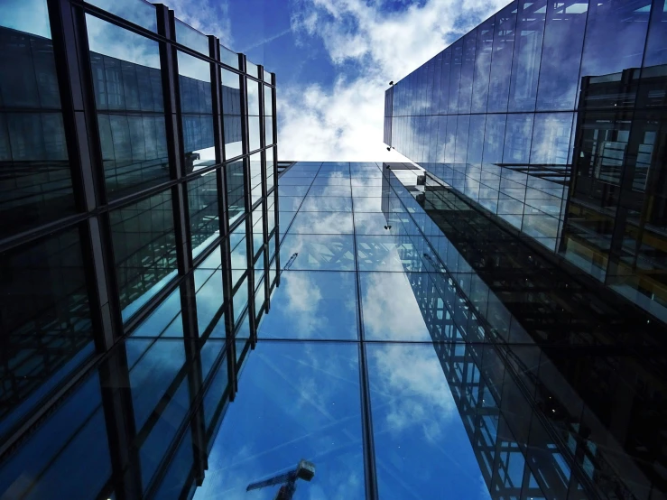 a plane flying through a blue sky next to tall buildings, a picture, inspired by Richard Wilson, pexels contest winner, modernism, person made out of glass, abstract mirrors, tall obsidian architecture, underwater looking up