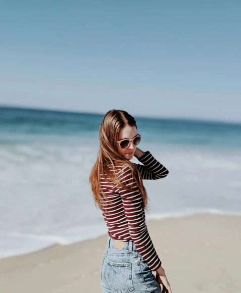 a woman standing on a beach next to the ocean, profile image, striped, instagram post, denim