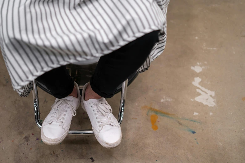 a person sitting in a chair with white shoes, by Helen Stevenson, trending on unsplash, process art, stripey pants, wearing white sneakers, standing in class, dirty linen robes