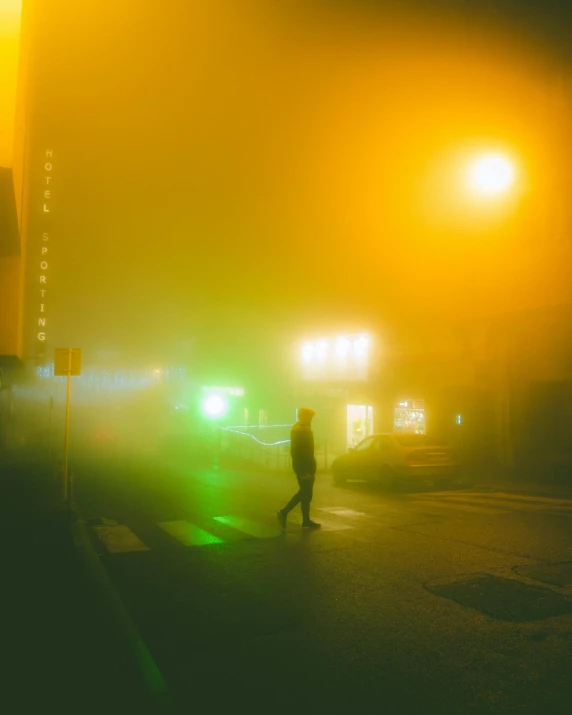 a person walking across a street at night, inspired by Elsa Bleda, with a yellow green smog sky, yellow aura, ((mist)), scene from a rave