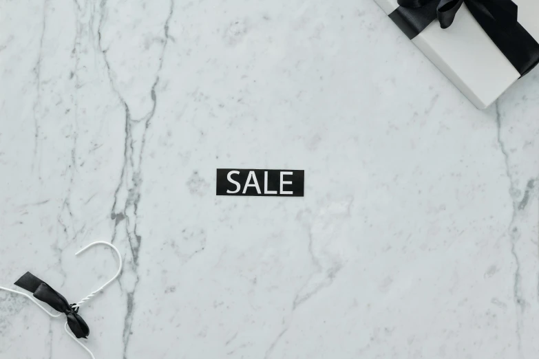 a black and white sale sign sitting on top of a marble counter, by Emma Andijewska, trending on unsplash, sticker - svg, background image, cables on floor, white marble texture