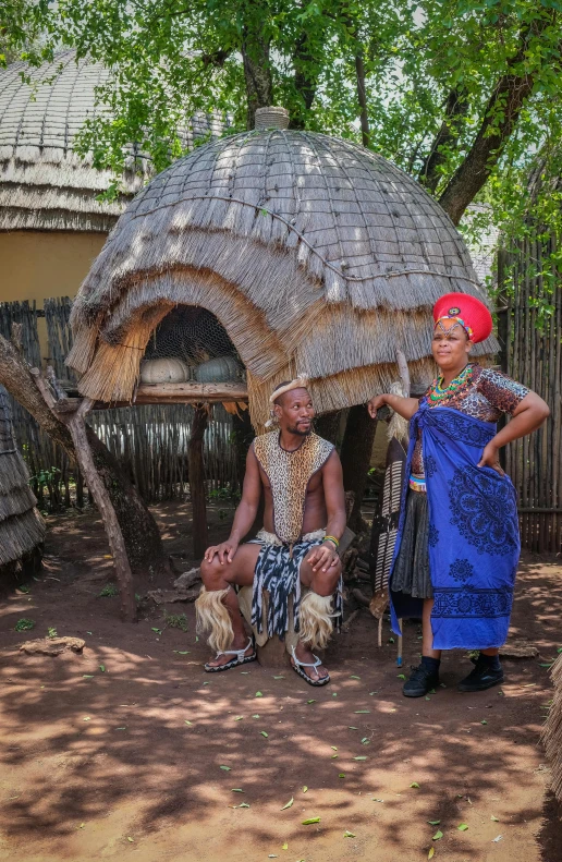 a group of people standing in front of a hut, elaborate costume, bushveld background, couple portrait, taken in 2 0 2 0