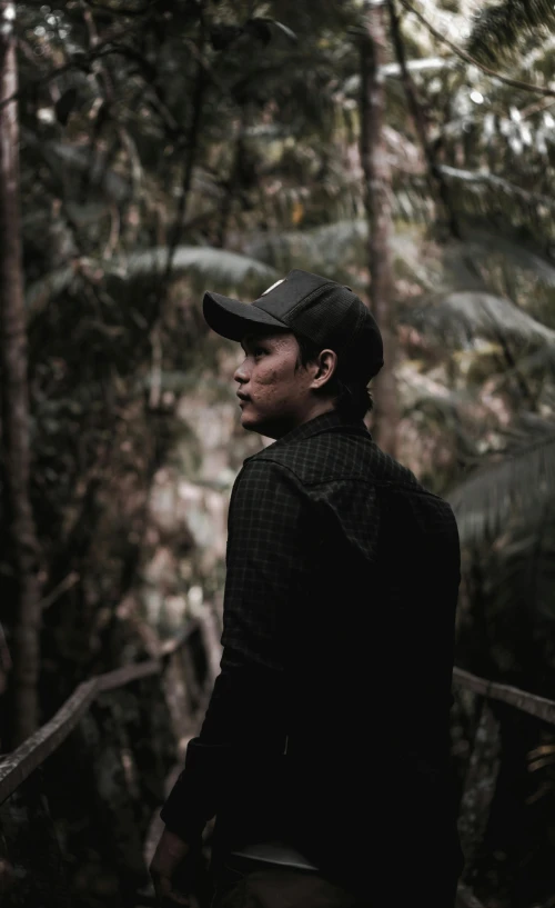 a man standing in the middle of a forest, unsplash, sumatraism, profile pose, low quality photo, dark. no text, ((portrait))