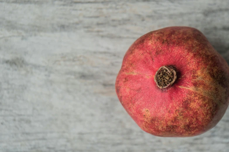 a pomegranate sitting on top of a wooden table, trending on pexels, on a pale background, background image, round-cropped, potato