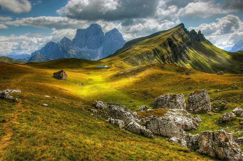 a grassy field with rocks and mountains in the background, pexels contest winner, renaissance, italy, stunning screensaver, brilliant peaks, post processed