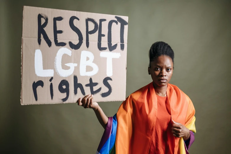 a woman holding a sign that says respect lgbt rights, trending on pexels, adut akech, white ribbon, thumbnail, brown