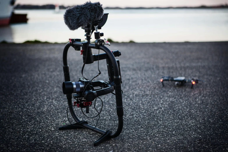 a video camera sitting on top of a tripod next to a body of water, unsplash, realism, landing gear, red and black robotic parts, cane, vehicle