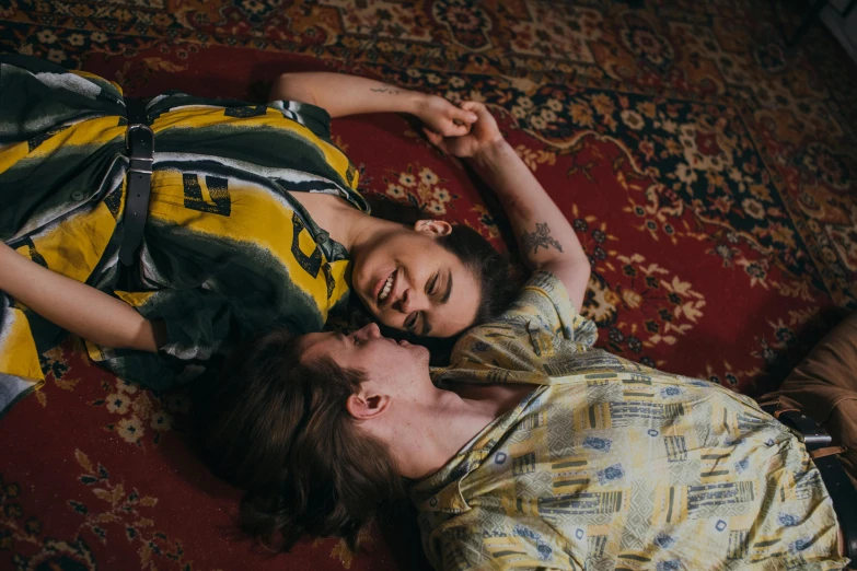 a man and a woman laying on a rug, inspired by Elsa Bleda, trending on pexels, lesbian, patterned clothing, vintage aesthetic, lesbian embrace
