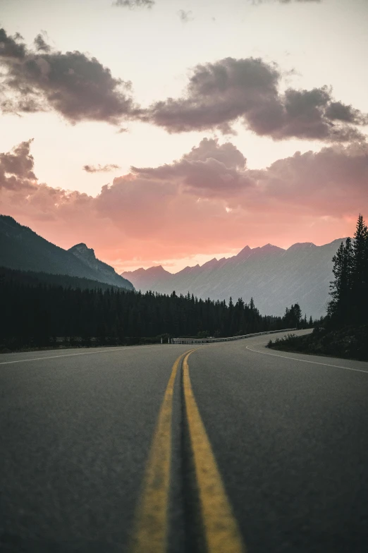 an empty road with mountains in the background, unsplash contest winner, banff national park, pink skies, 🚿🗝📝, plain stretching into distance