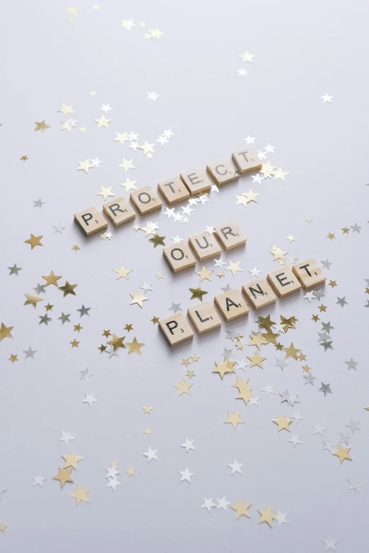 a couple of scrabbles sitting on top of a table, an album cover, by Julia Pishtar, pexels contest winner, planets and stars, sustainable materials, protection, bubble letters
