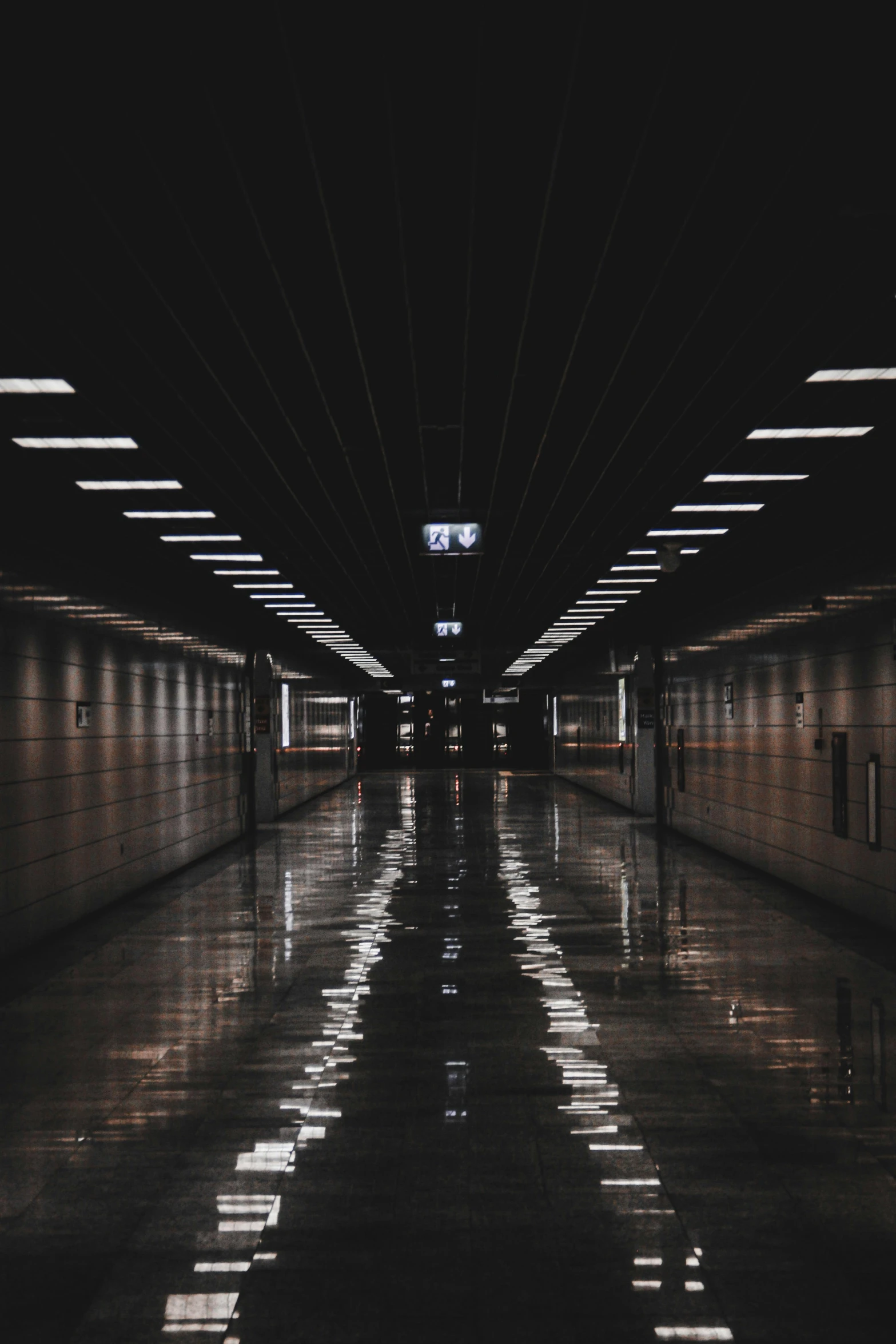 a black and white photo of a long hallway, inspired by Elsa Bleda, unsplash contest winner, flooded station, symmetric lights, at nighttime, looking sad