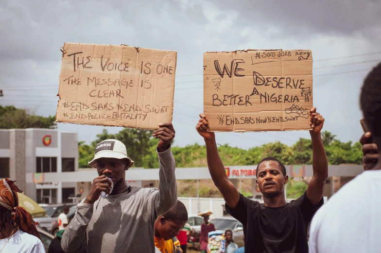 a group of people holding up signs at a protest, a photo, trending on unsplash, black arts movement, kano), two men, roadside, instagram story