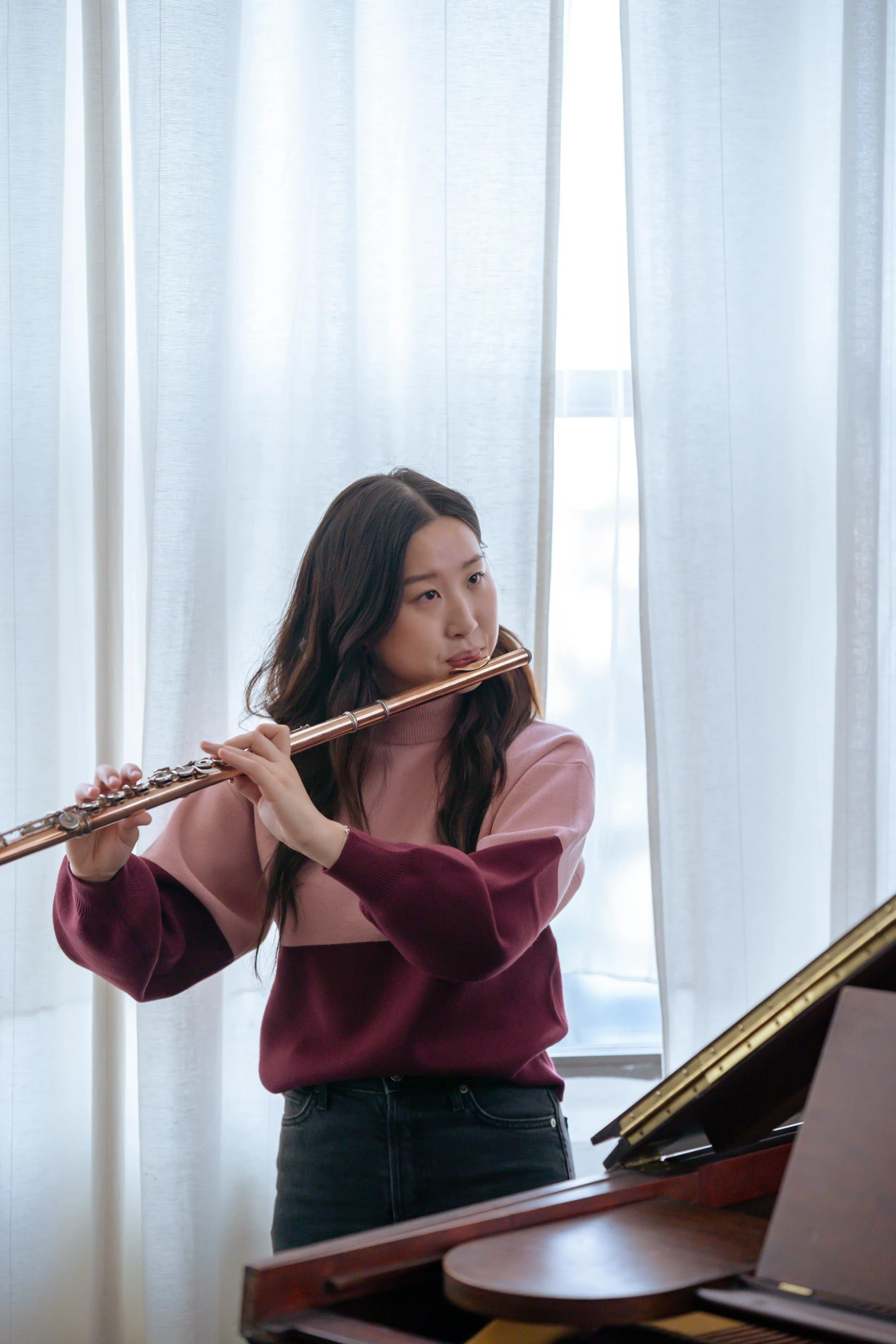 a woman playing a flute in front of a piano, jaeyeon nam, sydney hanson, 🚿🗝📝