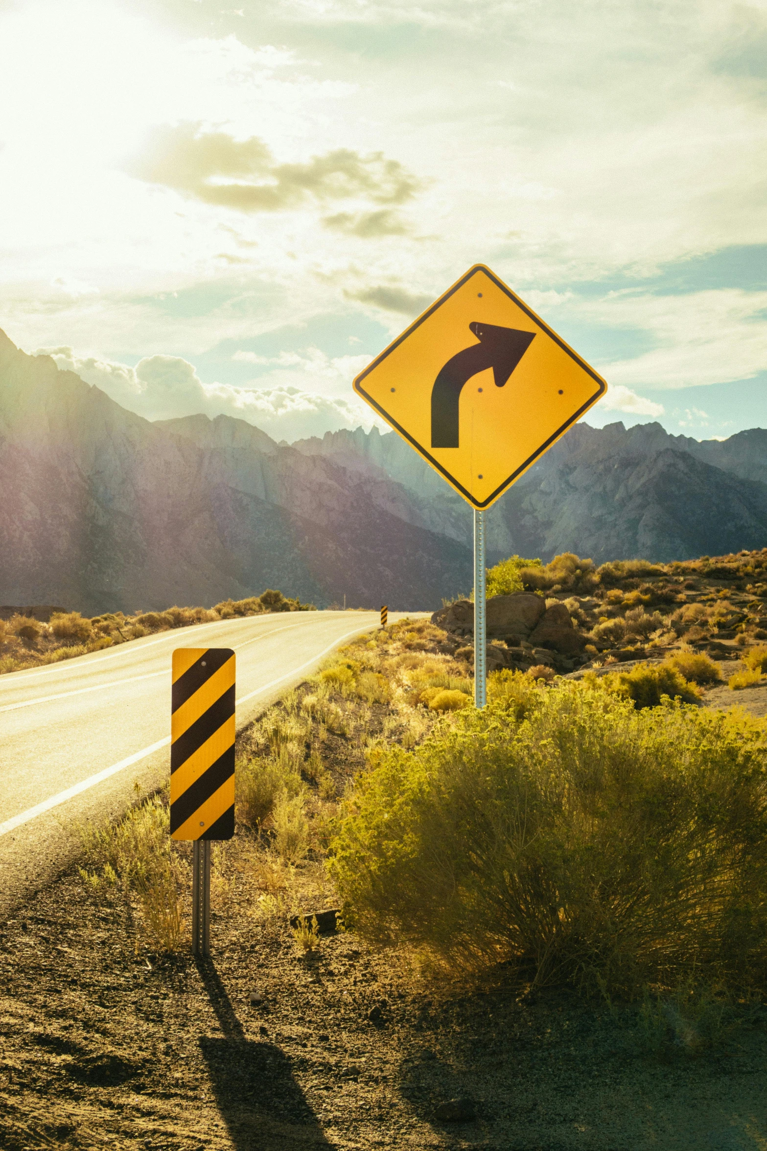 a yellow and black sign sitting on the side of a road, trending on unsplash, curved red arrow, mountains, square, grainy