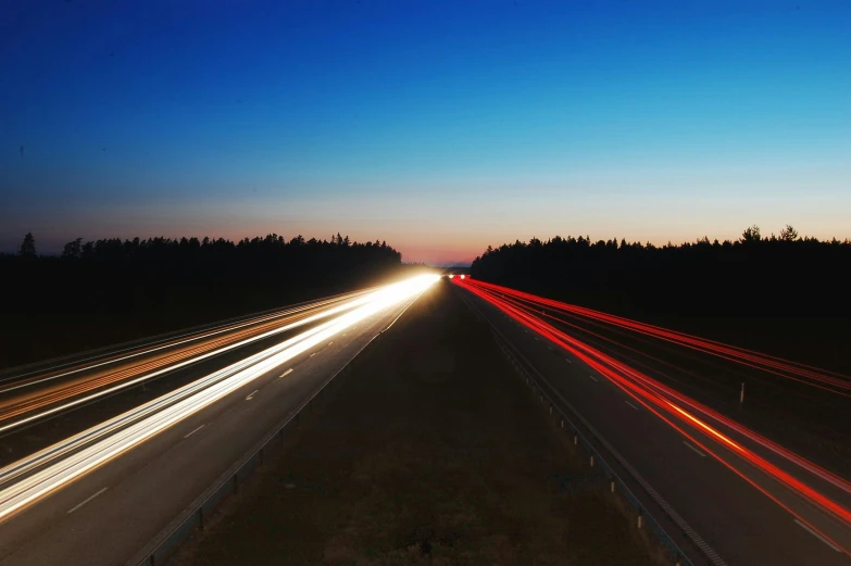 a highway filled with lots of traffic next to a forest, an album cover, unsplash, hurufiyya, blue and red lighting, running lights, summer evening, lines of energy