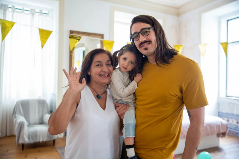 a man standing next to a woman and a child, pexels contest winner, antipodeans, unibrow, yellow hue, at home, celebration