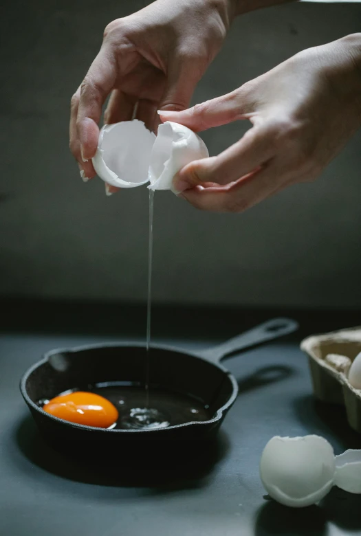 a person breaking an egg in a frying pan, by Jessie Algie, trending on unsplash, process art, ingredients on the table, dwell, studio photo, on a dark background