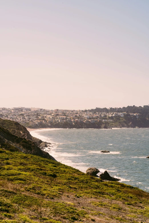 a bench sitting on the side of a hill next to the ocean, san francisco, jen atkin, city views, beaches