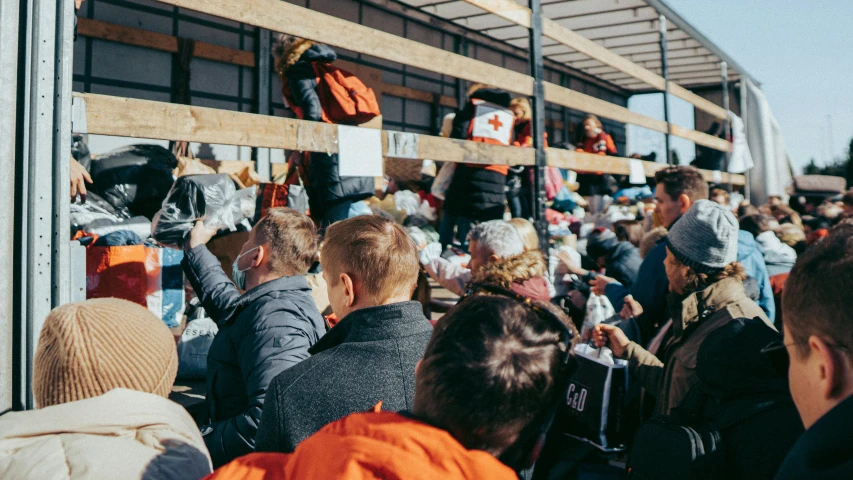 a group of people that are standing in front of a truck, by Tobias Stimmer, trending on unsplash, hurufiyya, the stadium has a full crowd, crates and parts on the ground, winter sun, signing autographs